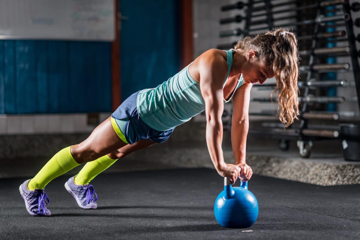 BCAA for women: athlete planking while using a kettlebell